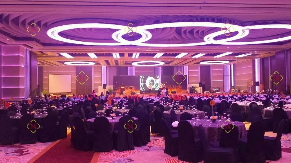 A corporate gala beneath circular ceiling lights and a magenta architectural wash